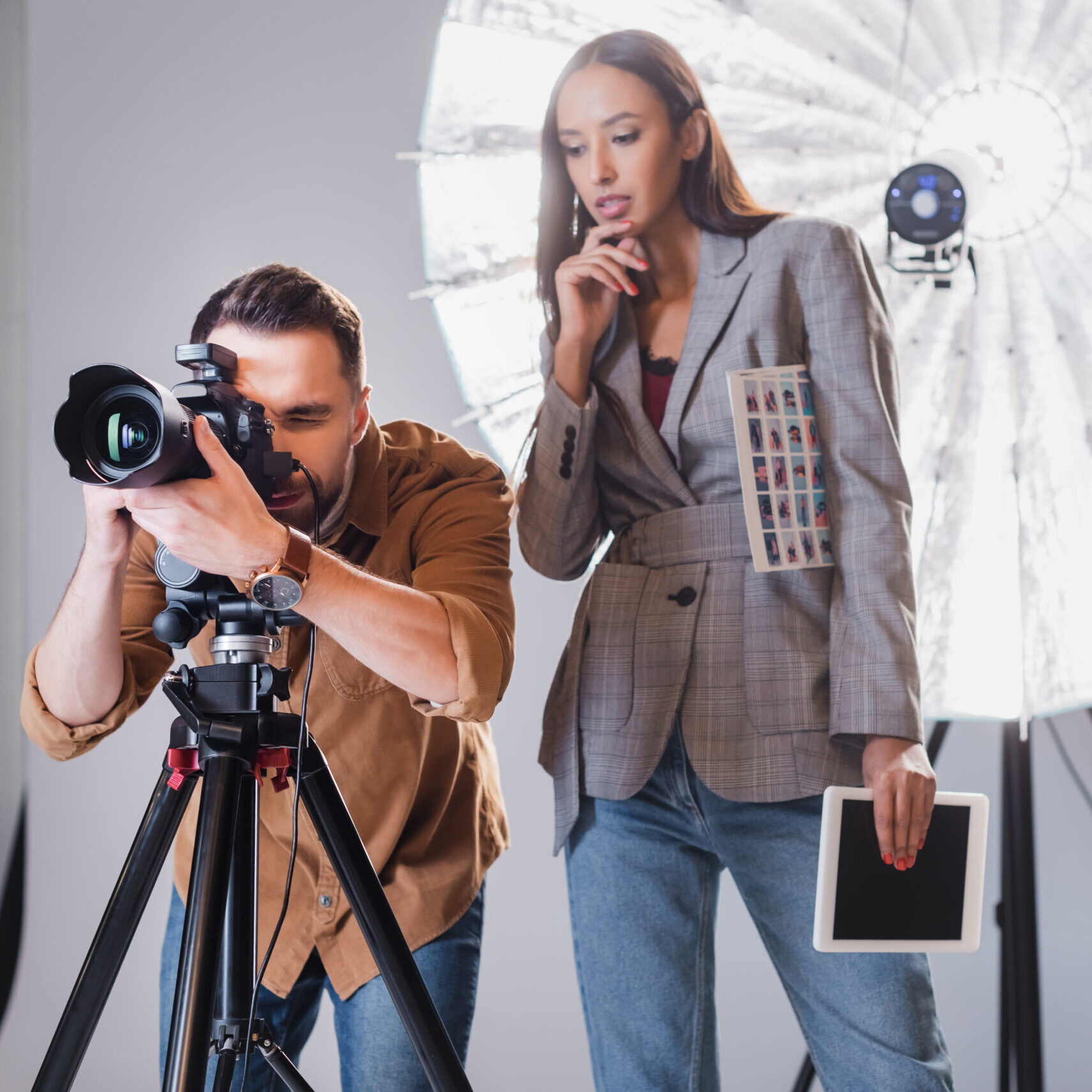 photographer taking photo and producer looking at digital camera on backstage